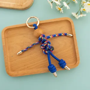 Detailed closeup shot of the handmade woven puppet keychain with colorful cord and wooden bead.