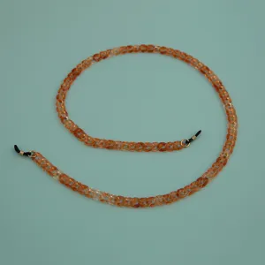 Detailed shot of amber acrylic eyeglass chain link, stylish eyewear strap accessory.
