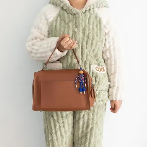Handcrafted rope puppet pendant brown leather handbag stylish cute charm detail view.