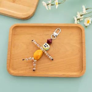 Close-up of handmade quirky beaded doll keychain, featuring painted face and crystal limbs.