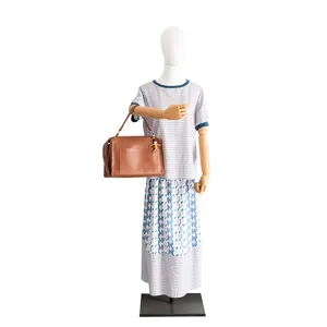 Detail shot of stylish brown leather handbag with cute doll charm displayed on mannequin.