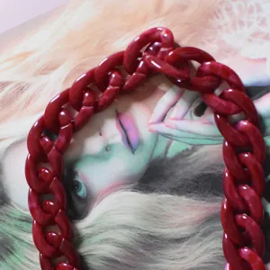 Red acrylic bag chain strap detail close up, stylish resin chunky handbag shoulder replacement accessories.