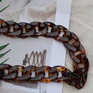 Detailed shot of medium tortoise shell acrylic chain bag strap, elegant accessory.