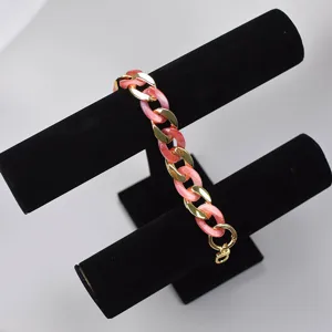 Detailed view of pink acrylic and gold metal chunky chain strap accessory for bags and phones.