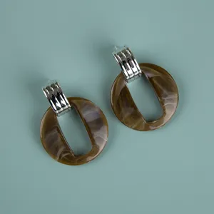 Oversized brown acrylic drop earrings with silver metal top, stylish fashion jewelry detail.