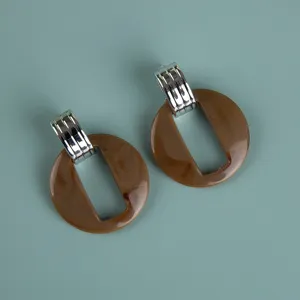 Close-up detail of large brown acrylic geometric dangle earrings with silver top.