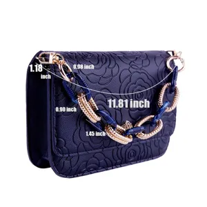 Detailed view of dark blue embossed flower handbag with unique acrylic and gold chain links.
