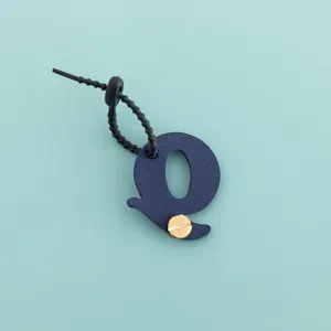 Gros plan sur le porte-clés lettre q en cuir PU bleu avec vis dorée élégante.