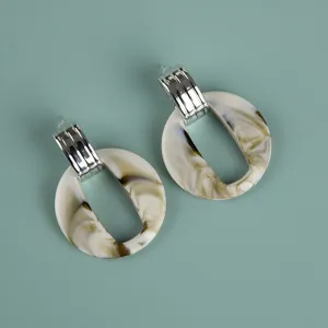Detailed close-up view of oversized acrylic marbled hoop earrings with metallic top styling.