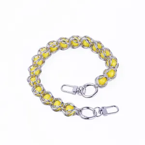 Detail shot of metal chain with yellow acrylic beads and metal clasps for DIY bag accessories.