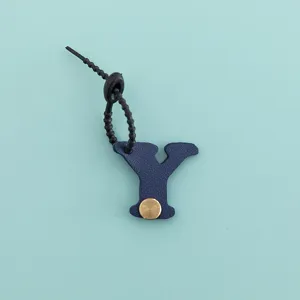 Vue détaillée du pendentif porte-clés lettre Y en cuir PU bleu avec bouton-pression doré.