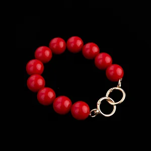 Detailed close-up view of red round bead handbag strap accessory featuring gold metal rings.