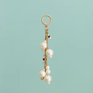 Close-up detail of the stylish pearl bag charm featuring golden metal chains and mixed resin pearls.