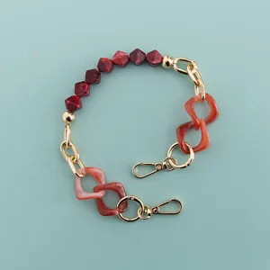 Detailed view of the short red resin and gold metal multi-functional phone chain strap.