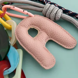 Close-up detail of pink leather letter A pendant, DIY bag charm and phone chain accessory.