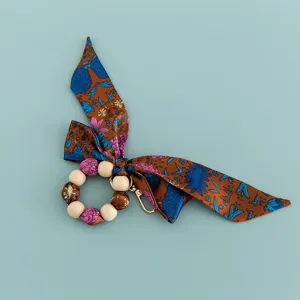 Detail shot of creative silk scarf beaded bow wooden bead keychain bag charm accessory.
