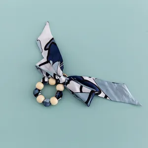 Blue patterned silk scarf wooden bead bow keychain accessory and bag decoration detail shot.