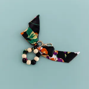 Wooden bead and floral silk scarf bow keychain detail shot, showing cute bag charm and hardware.