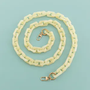 Dettaglio catena in acrilico, maglie quadrate beige con chiusure metalliche dorate per borse.