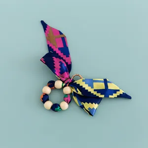 Creative silk scarf wooden bead bow keychain and bag charm accessory with geometric print.