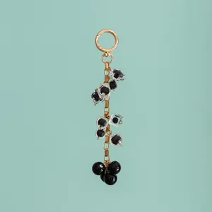 Close-up detail of luxury black and clear resin beads with gold chain bag charm keychain.
