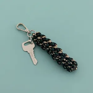 Detailaufnahme des geflochtenen Nylonseil-Taschenanhängers und Metall-Schlüsselanhängers.