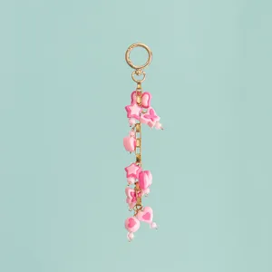 Detailed view of the pink resin star and heart charm bag pendant with gold tone chain.