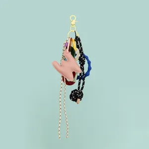 Close-up detail of DIY leather letter keychain charm with woven cord and colorful resin rings