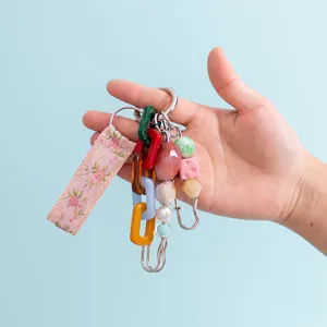 Detailed view of colorful macaron beaded keychain charm, floral fabric strap and metal links.