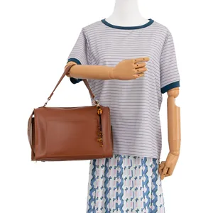 Brown leather handbag for women, stylish shoulder bag with front pocket and decorative pendant.