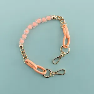 Close-up detail of the pink heart bead and gold metal chain phone strap accessory.