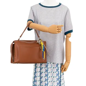 Brown leather shoulder handbag with stylish sports charms and comfortable top handle.