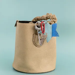 Detail view of stylish beige PU leather bucket bag featuring a blue star charm and keys.