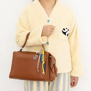 Brown leather handbag detail featuring stylish tennis racket keychain pendant for women.