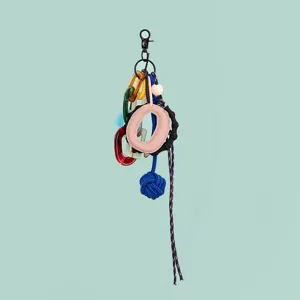 Detail view of a multi-element DIY bag charm with resin links, leather ring, and blue knot.