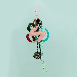 DIY leather letter bag charm with resin links, woven ropes, and bamboo-style rings.
