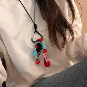 Detailaufnahme einer niedlichen Mehrlement-Anhänger-Halskette mit Kamm und Erdbeer-Charm.