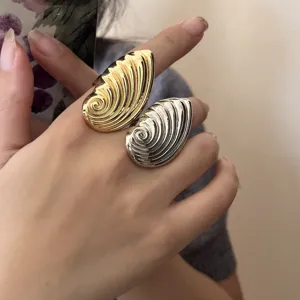 Nahaufnahme von übergroßen Spiralschalenringen in Gold und Silber, elegante Metallmode.