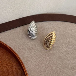 Detailansicht von stilvollem muschelförmigem Metallschmuck in Silber und Gold, modernes Design.