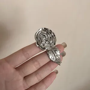 Detailansicht eines silbernen Rosenblüten- und Blatt-verstellbaren Rings an einem Finger.
