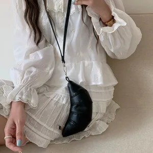 Primo piano di una mini borsa croissant in pelle nera al collo e accessorio moda chic.