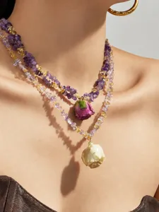 Nahaufnahme der zweifarbigen Kristallperlenkette mit Harz-Rosenanhänger in vergoldetem Design.