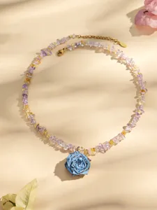 Nahaufnahme der Harz Rosen Halskette mit bunten Kristallsplittern vor warmer beige Kulisse.