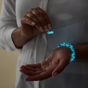 Luminous starry glass crystal healing bead bracelet and earrings glowing in dark blue light.