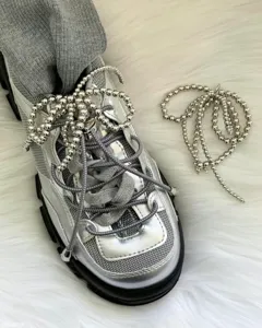 Silver metallic sneakers detailed with stunning pearl beaded shoelaces and cute bow tassel accessories.