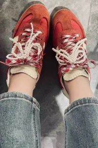 Red casual sneakers featuring pearl bow shoelaces and stylish embroidered details for women.