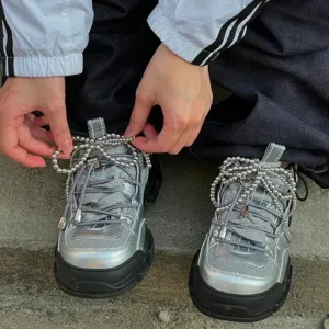 Silver chunky sneakers with beaded bow laces, trendy street style fashion footwear accessories.