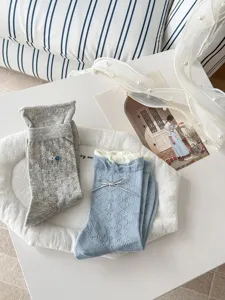 Detailed view of cute bow and floral knit socks, soft cotton fabric, perfect cozy style.