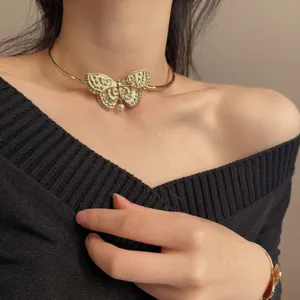 Gedetailleerd opname van een vintage gouden metalen vlinder choker ketting met parel.