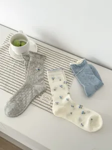 Detailed view of Korean style floral and bow mid-calf socks arranged on a clean white desk surface.